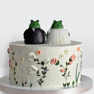 0 Свадебный торт с фигурками жениха и невесты в виде лягушек с цветами с оригинальным декором и игривой композицией